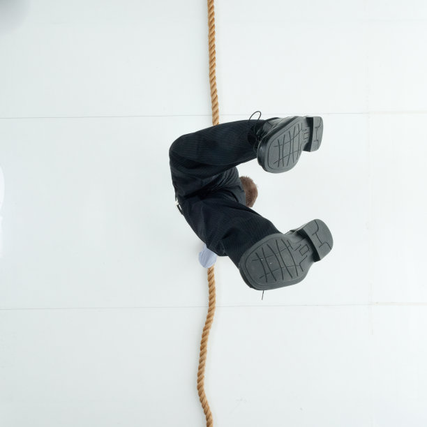 白人男性商人倒立在白色背景前，穿着衬衫，积极进行运动训练并使用绳子图片下载