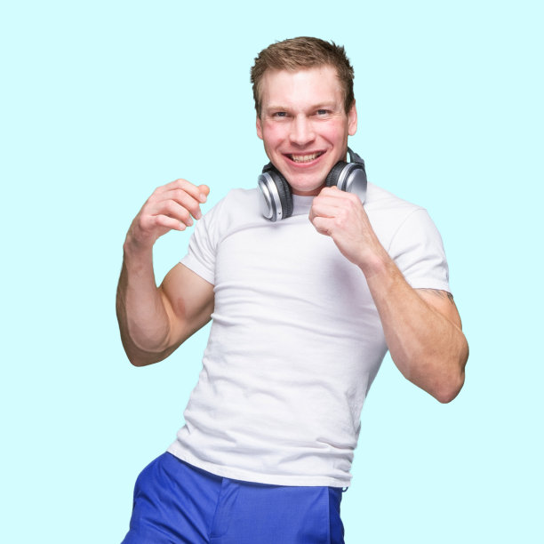 白人年轻男性穿着衬衫戴着耳机在蓝色背景下锻炼图片下载