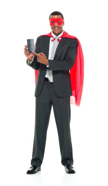 非裔美国人种族的年轻男性英雄站在白人背景前，戴着面具伪装，使用智能手机图片下载