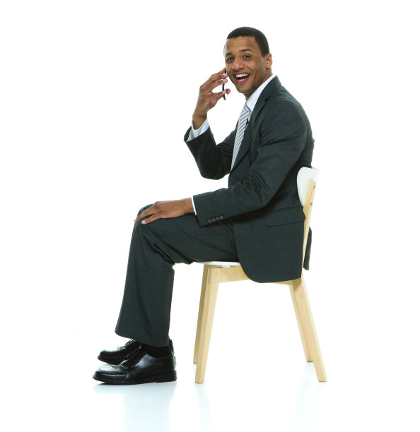 非裔美国年轻男性商人坐在白色背景下穿着商务装，使用智能手机图片下载