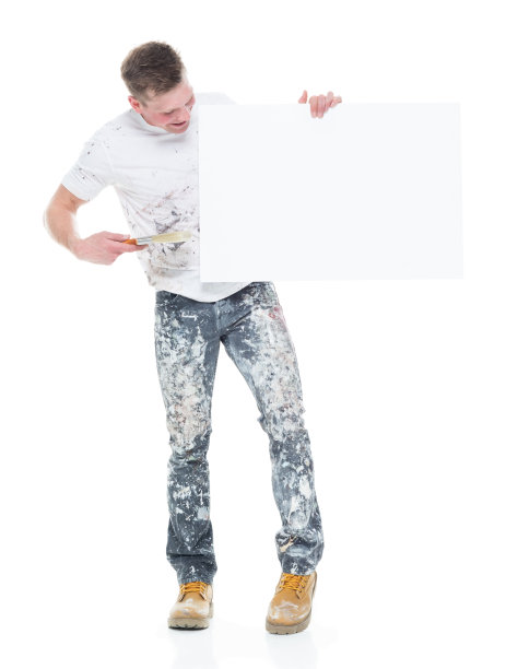 白人年轻男性房屋油漆工站在白色背景前，举着标牌图片下载