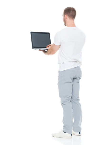 白人男性穿着裤子站在白色背景前使用笔记本电脑图片下载
