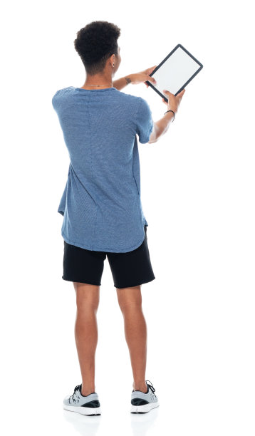 z一代十几岁的男孩穿着运动鞋，用触摸屏站在白色背景前图片下载