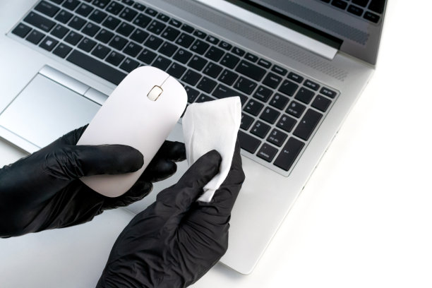 女士戴着黑手套，用抗菌湿布擦拭电脑鼠标。办公室消毒俯视图。病毒防护图片下载