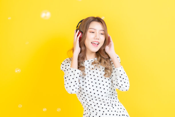 美丽的年轻女子邀请亚洲人愉快地戴着耳机听音乐。图片下载