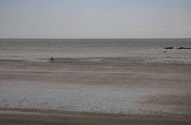 一个令人惊叹的，宁静的风景，空的海滩淡季和一个人散步在远处的剪影，英国康沃尔。图片下载