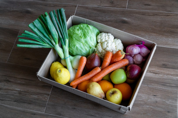 新鲜蔬菜在纸板箱在棕色的木头背景。图片下载