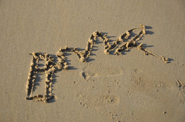 夕阳西下，未知的字母在沙滩上的湿沙上画着图片下载