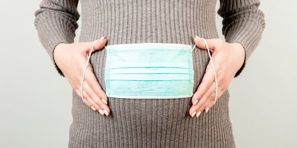一个怀孕女孩肚子上的医用口罩横幅。hild保护。冠状病毒、covid-19、检疫的概念图片下载