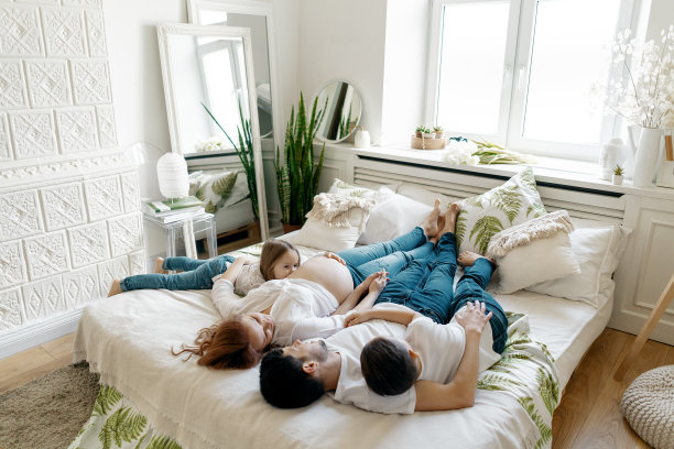 幸福怀孕的一家人躺在家里的床上图片下载