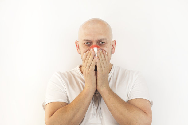 流鼻涕和过敏的概念。秃头的男人用餐巾纸擦鼻子。图片下载