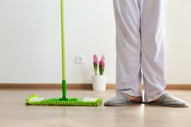 绿色拖把和腿放在木地板上。家庭设备图片下载