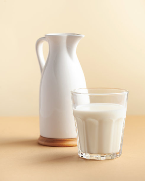 棕色背景上的牛奶和送奶工。极简主义。农场乳品的概念，牛奶日。副本的空间。图片下载