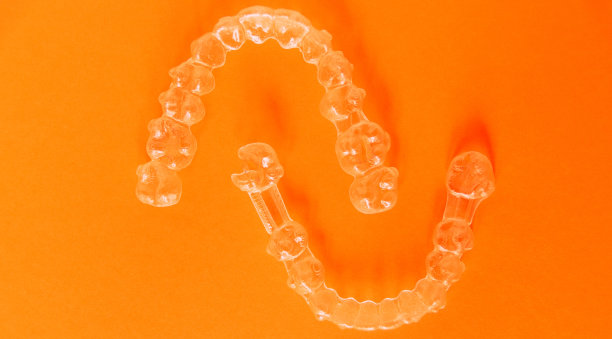 橙色背景上的两个透明牙齿对准器的样本。图片下载