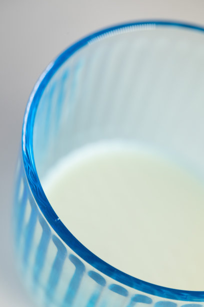 牛奶在浅蓝色的玻璃里面，白色的背景图片下载