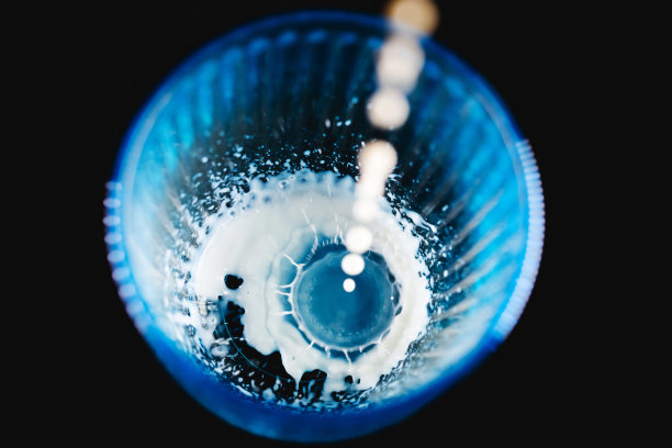 牛奶倒在黑色背景的浅蓝色玻璃里图片下载