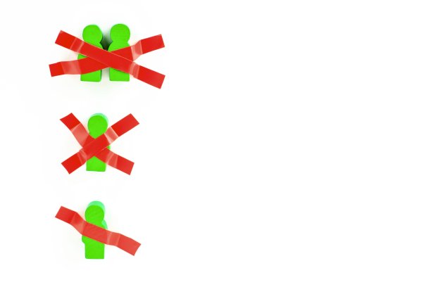 玩具木制的人用胶带粘在白色的墙上。在新冠肺炎大流行期间保持身体隔离、在家、社交距离、隔离、强制隔离、禁闭的概念。图片下载