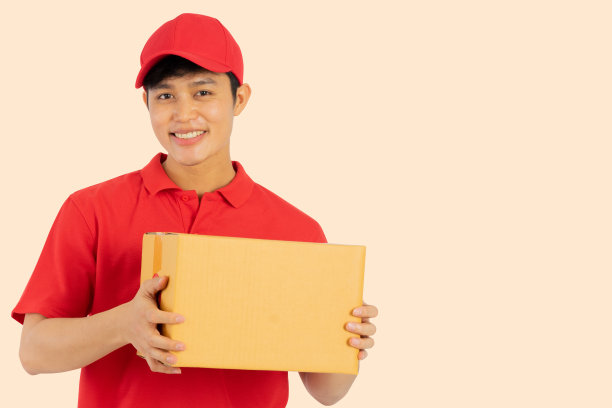 近距离的年轻邮政工人(红色制服)携带盒子隔离在令背景给客户，商业和电子商务在检疫生活理念图片下载