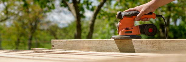 一个面目全非的人在花园里打磨木板。DIY家居装修，装修，木工概念。手细节横幅与复制空间。图片下载