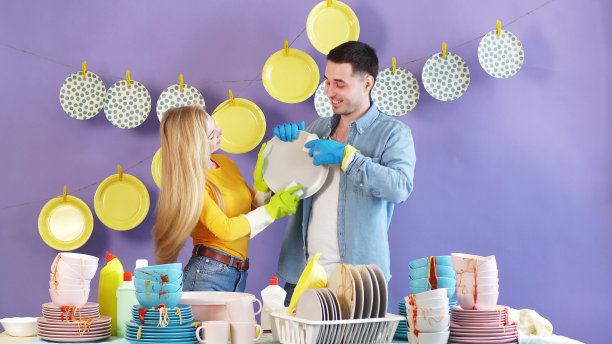 一对年轻夫妇，一男一女，看着对方，洗碗擦盘子。幸福，家人一起做一切事图片下载