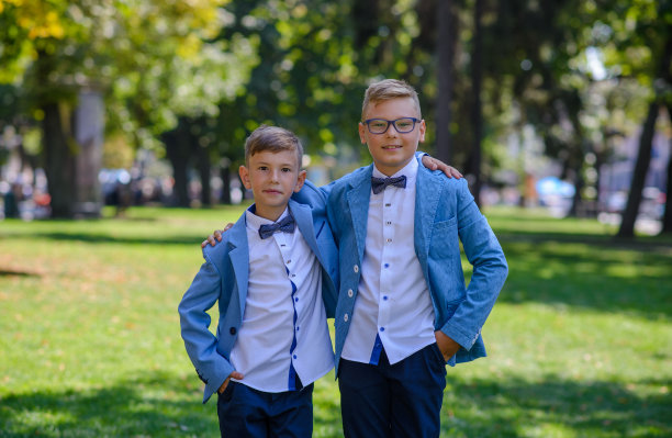 两个小男孩，弟弟都穿了西装。孩子们站在公园里互相拥抱。图片下载
