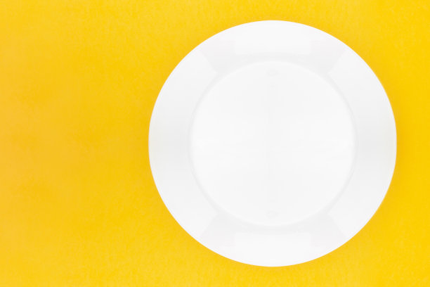 黄色背景上的空白白色餐盘。前视图。空白的设计与复制空间。图片下载
