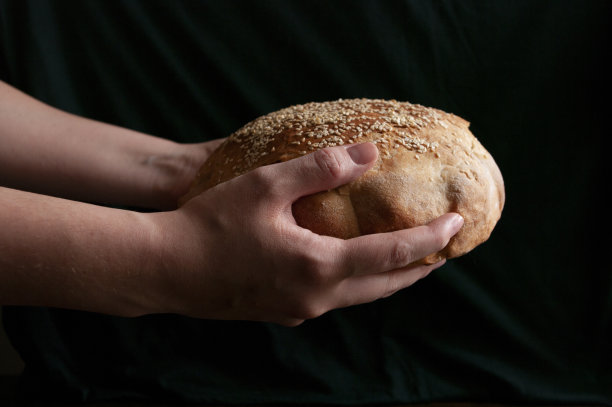 女性手拿新鲜出炉的酸面包。图片下载