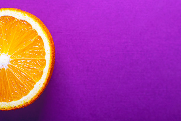 在明亮的淡紫色背景上的半张橙色特写。图片下载