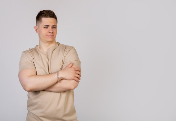 年轻男子双手交叉在胸前，脸上的表情很普通。图片下载