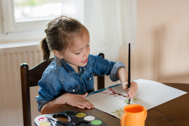 小女孩专注于在自然环境的木桌上画一幅彩色的画图片下载