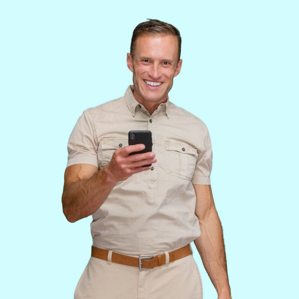 白人体力劳动者站在蓝色背景前，拿着包裹，使用智能手机图片下载