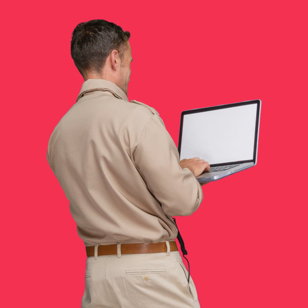 白人男性警察站在有色背景下佩戴警徽并使用电脑图片下载