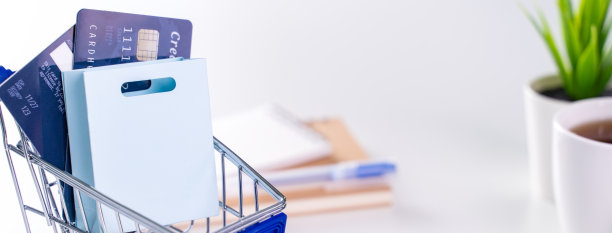 办公室在线支付，在家购物，电子支付与信用卡的概念，笔记本电脑在白色的桌子背景与购物车。图片下载