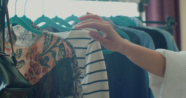 地板上有一个衣架，用来挂衣服。衣架与不同颜色的妇女衣服的背景，全景窗口，特写。图片下载