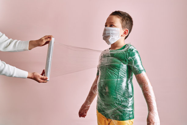 母亲正在给儿子包裹，以预防冠状病毒感染。图片下载