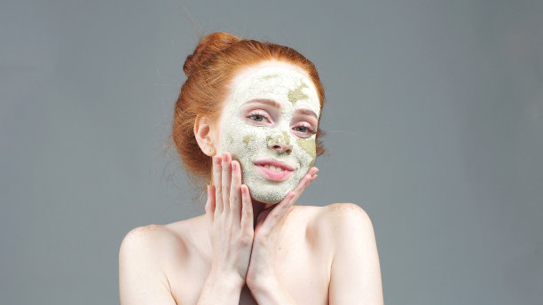 美容治疗。那个女孩正在用绿色粘土面膜敷脸。审美过程图片下载