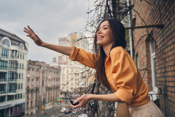 快乐的女士站在阳台上问候朋友图片下载