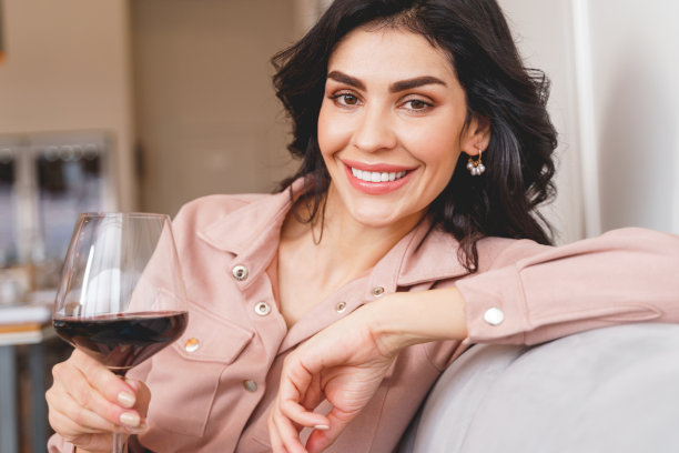 漂亮的黑发女士拿着酒杯微笑着图片下载