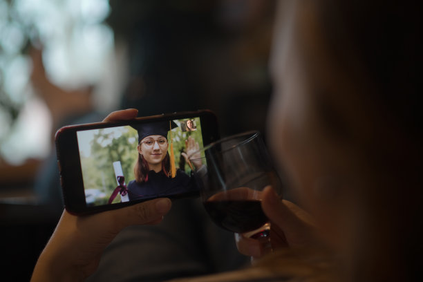 十几岁的女孩穿着毕业礼服和帽子在视频电话问候她的亲戚或朋友图片下载