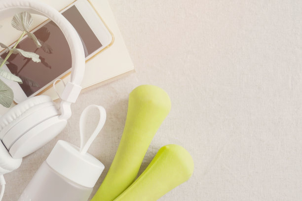 绿色哑铃，水瓶，智能手机和耳机，在家锻炼训练，在线流媒体视频锻炼，社交距离，新常态概念图片下载