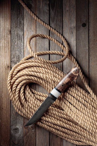 猎人战斗手工刀和麻绳木制背景。图片下载