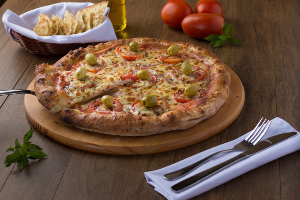 用意大利面、番茄片、马苏里拉芝士、牛至、火腿和绿橄榄做成的保利斯塔风味的木板披萨。提供一片披萨。起源于意大利的食物。2环境照片。图片下载