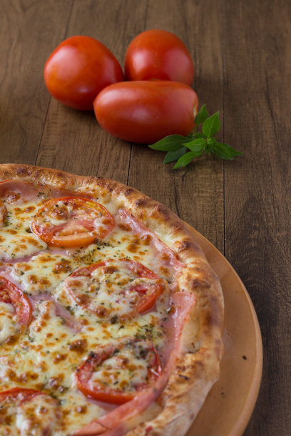 用意大利面、切片、番茄、马苏里拉芝士、牛至、火腿和绿橄榄做成的保利斯塔风味的木板披萨。罗勒叶意大利的典型食物。垂直的亲密照片。图片下载