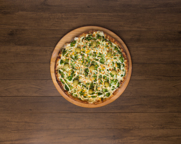 美味的西兰花披萨在木板上。与马苏里拉奶酪、西兰花、玉米、豌豆、橄榄和酱汁一起烘烤。上面的横放照片，中间是披萨。图片下载