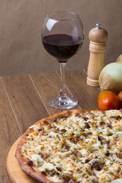 肉披萨放在木板上。由马苏里拉奶酪，picanha肉，洋葱，奶酪，番茄酱制成。菲力牛排，肉，胡椒粉，一杯红酒。披萨面团的垂直照片。图片下载