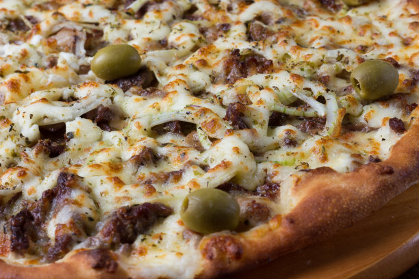 肉披萨放在木板上。由马苏里拉奶酪，picanha肉，洋葱，奶酪，番茄酱和橄榄制成。菲力牛排,肉。配料的微距照片。图片下载