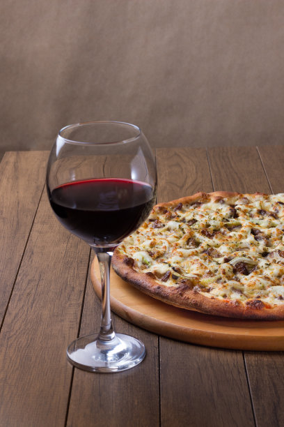 美味的肉披萨放在木板上。由马苏里拉奶酪，picanha肉，洋葱，奶酪，番茄酱制成。菲力牛排,肉。杯酒。餐厅的照片。图片下载