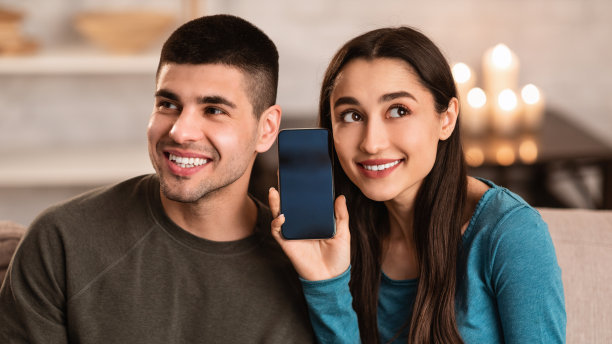 一对夫妇坐在家里的沙发上玩手机图片下载