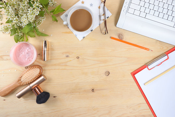 现代女性的办公桌，家庭办公室。电脑，春天的花和化妆品放在一个轻便的桌子上。简约的商业理念，家的舒适，俯视图，平铺，图片下载