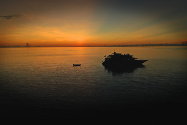 码头上一个日落男子在海边钓鱼的剪影。图片下载